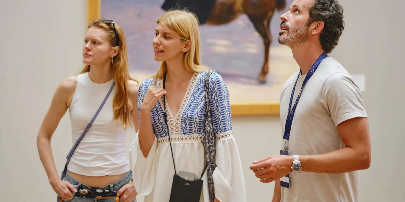 Visitors listening to their guide beside paintings