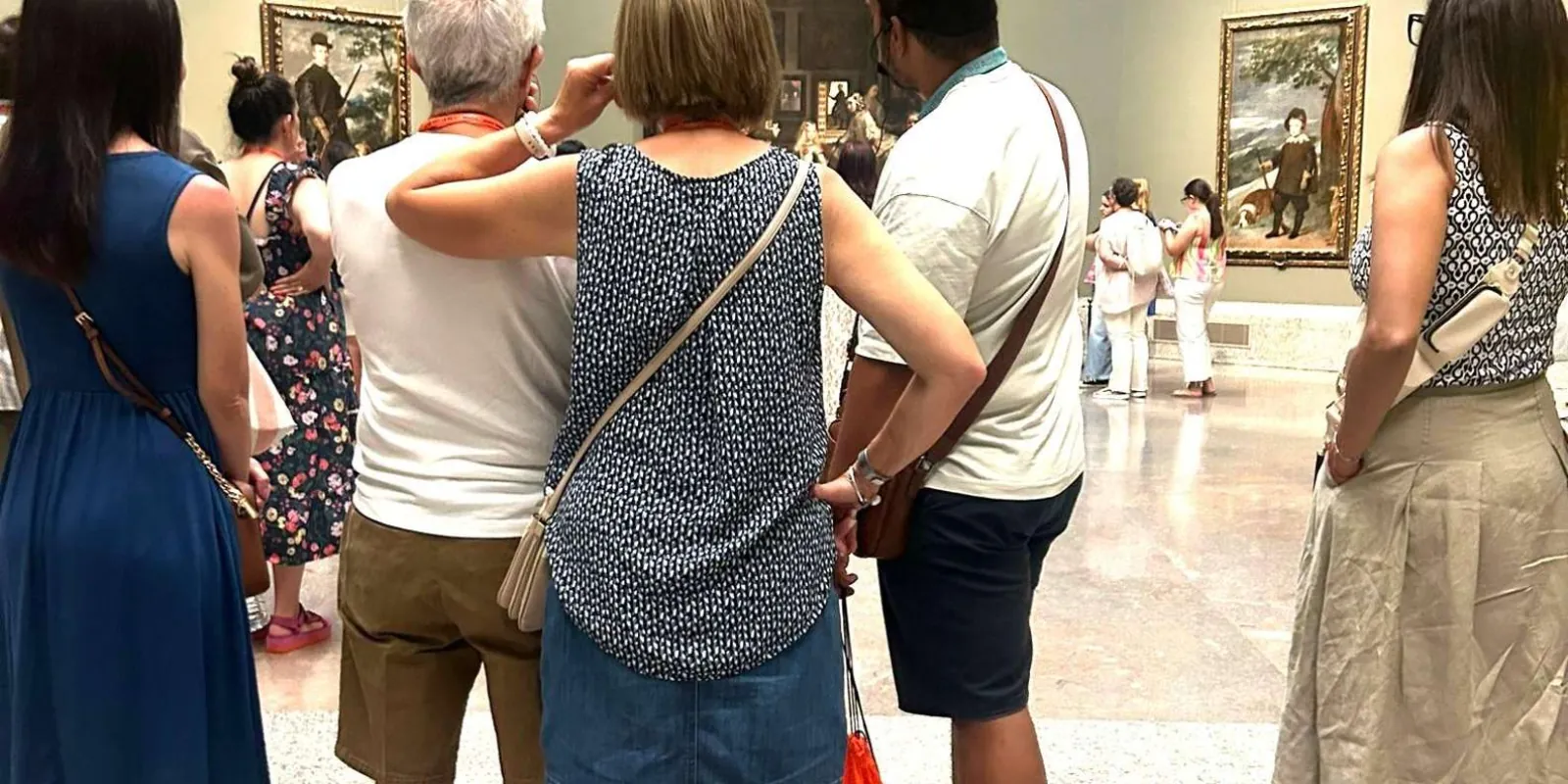 Visitors listening to a guide in a painting gallery